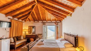 Un dormitorio con techo de madera, cama, escritorio, silla, sofá y vistas a través de una puerta.