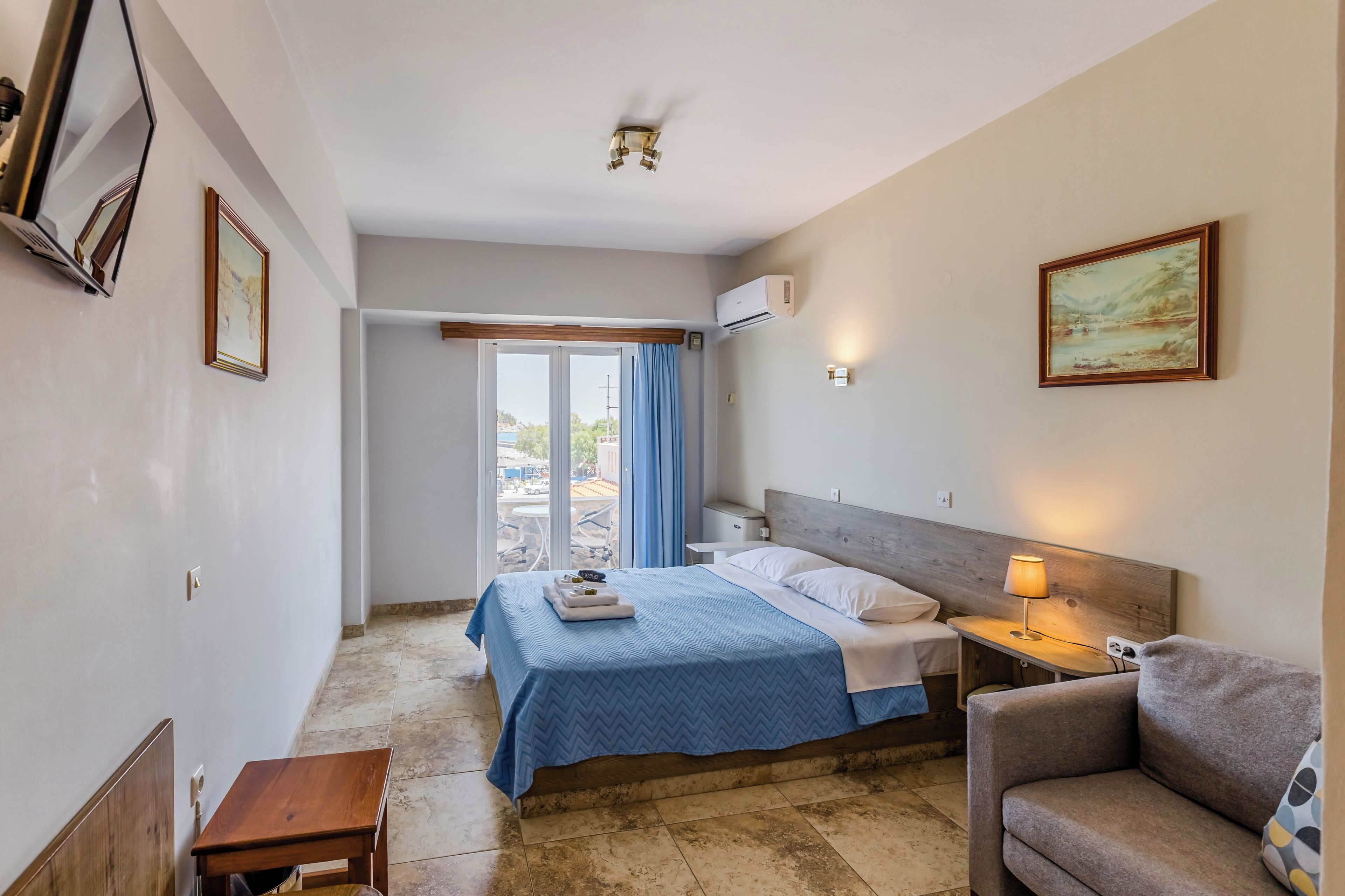A hotel room with a bed, a desk, a chair, a TV, and a window with curtains.