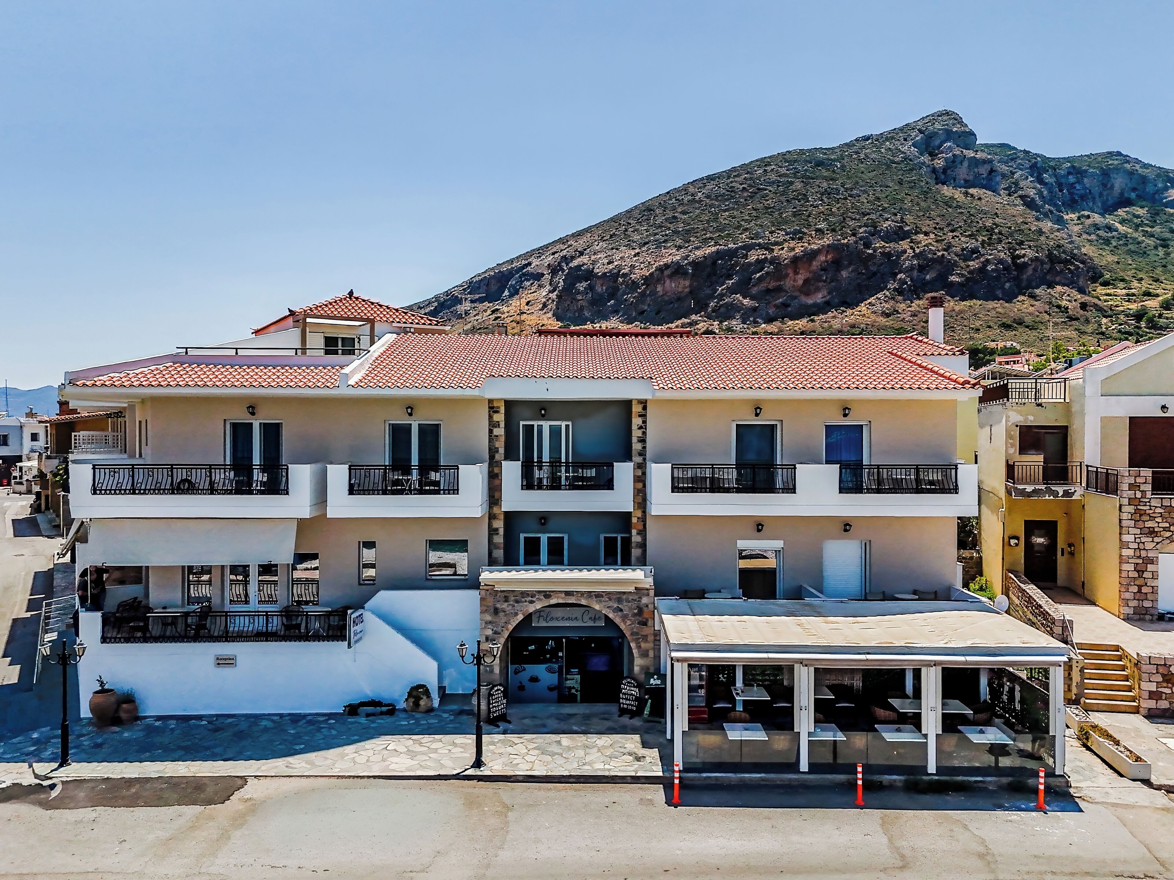 A multi-story hotel with balconies, a covered outdoor seating area, and a mountain backdrop.