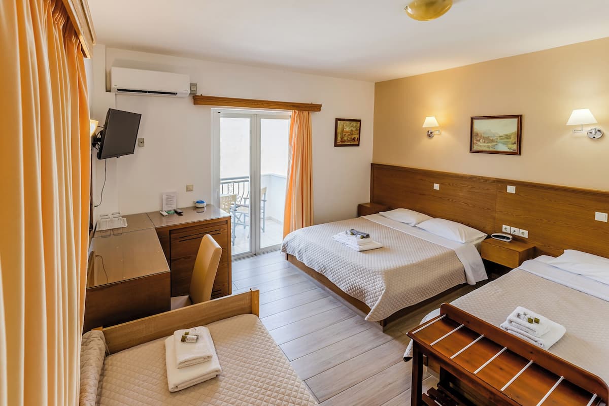 A hotel room with two beds, a desk, a chair, a TV, and a balcony.