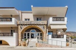 A two-story building with a stone archway entrance, balconies with metal railings, and a clear view of the surrounding landscape. - Filoxenia Hotel (Monemvasia)