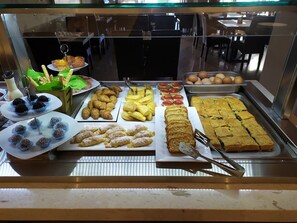 A buffet with various food items including pastries, fruits, and a large tray of baked goods. - Hotel Vizantio (Katerini)