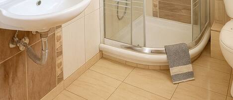 A bathroom with a glass-enclosed shower, a sink, and a toilet.