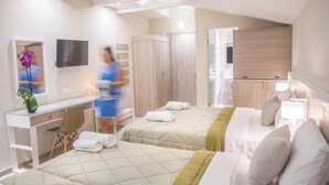A hotel room with two beds, a desk, a TV, and a bathroom.
