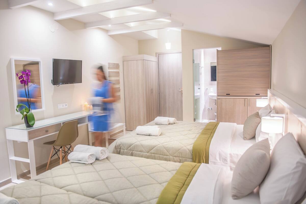 Ein Hotelzimmer mit zwei Betten, einem Schreibtisch, einem Fernseher und einem Badezimmer.