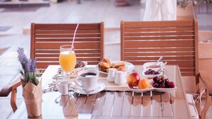 A breakfast setup with a table, chairs, and a variety of food and drink items.