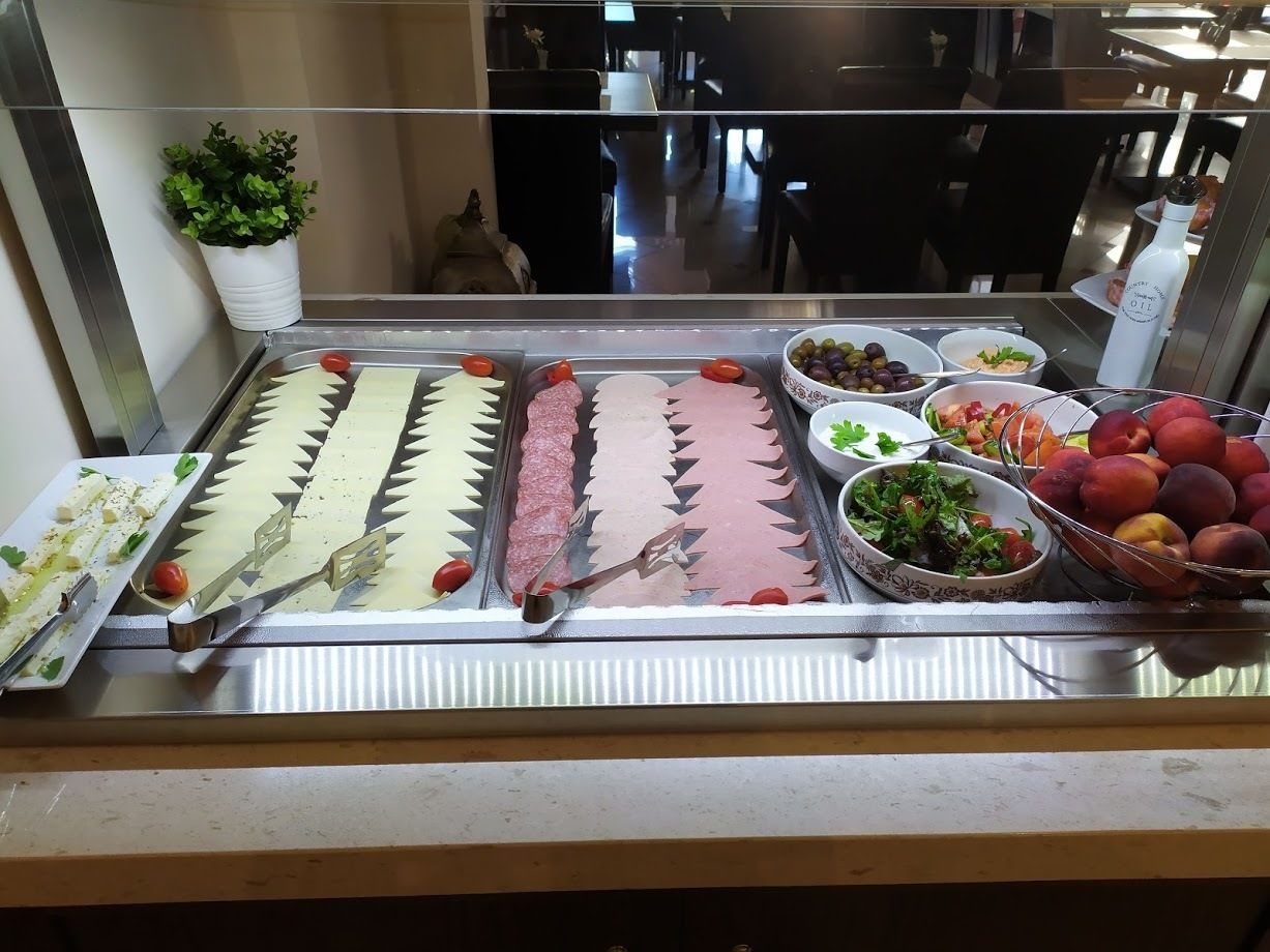 A buffet with various food items including sliced meats, cheeses, and fruits.