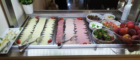 A buffet with various food items including sliced meats, cheeses, and fruits.