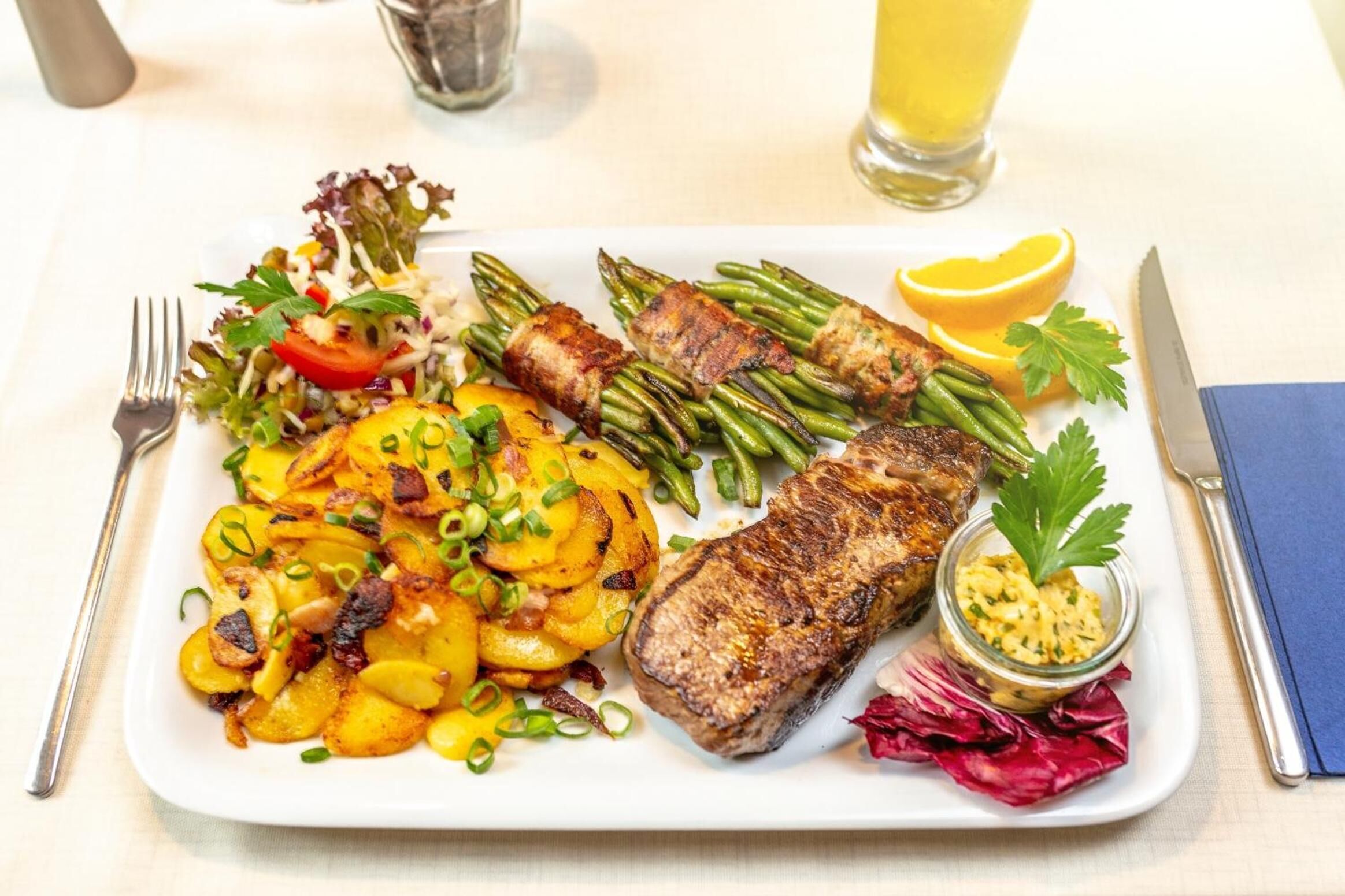 A plate of food including steak, green beans, potatoes, and a salad.