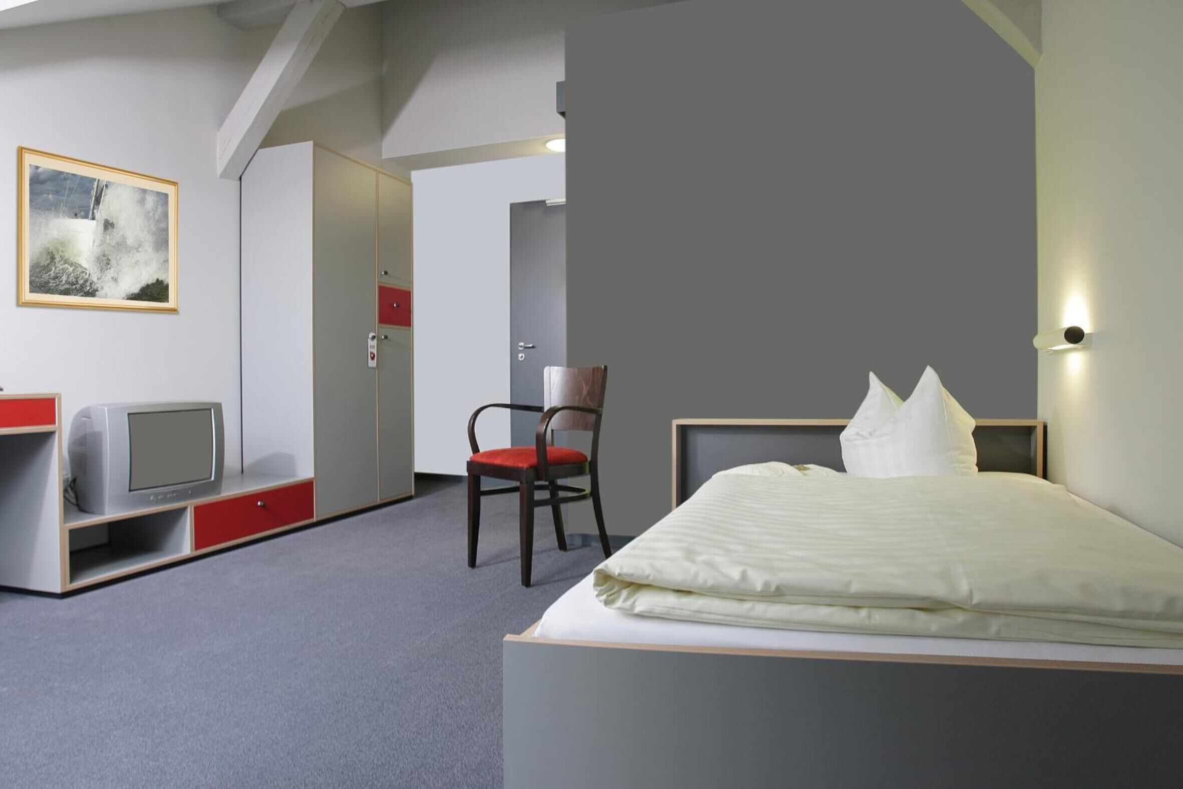 A hotel room with a bed, a television on a stand, a chair, and a painting on the wall.