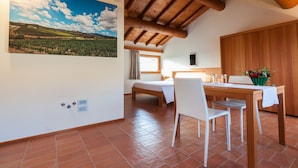 Une pièce comprenant un lit, une table à manger avec des chaises, un plafond en bois et un grand tableau représentant un paysage accroché au mur.