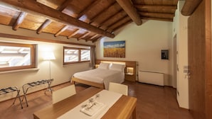 Une chambre avec un plafond en bois, un lit, des tables de chevet, un bureau avec un plateau et une fenêtre avec des rideaux.