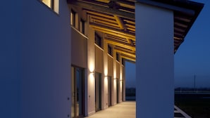 Un bâtiment moderne doté d’une passerelle couverte et de fenêtres illuminées au crépuscule.