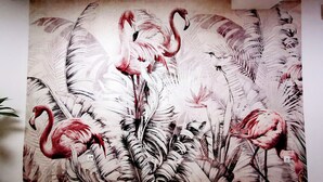 Una pared con un mural de flamencos y follaje.