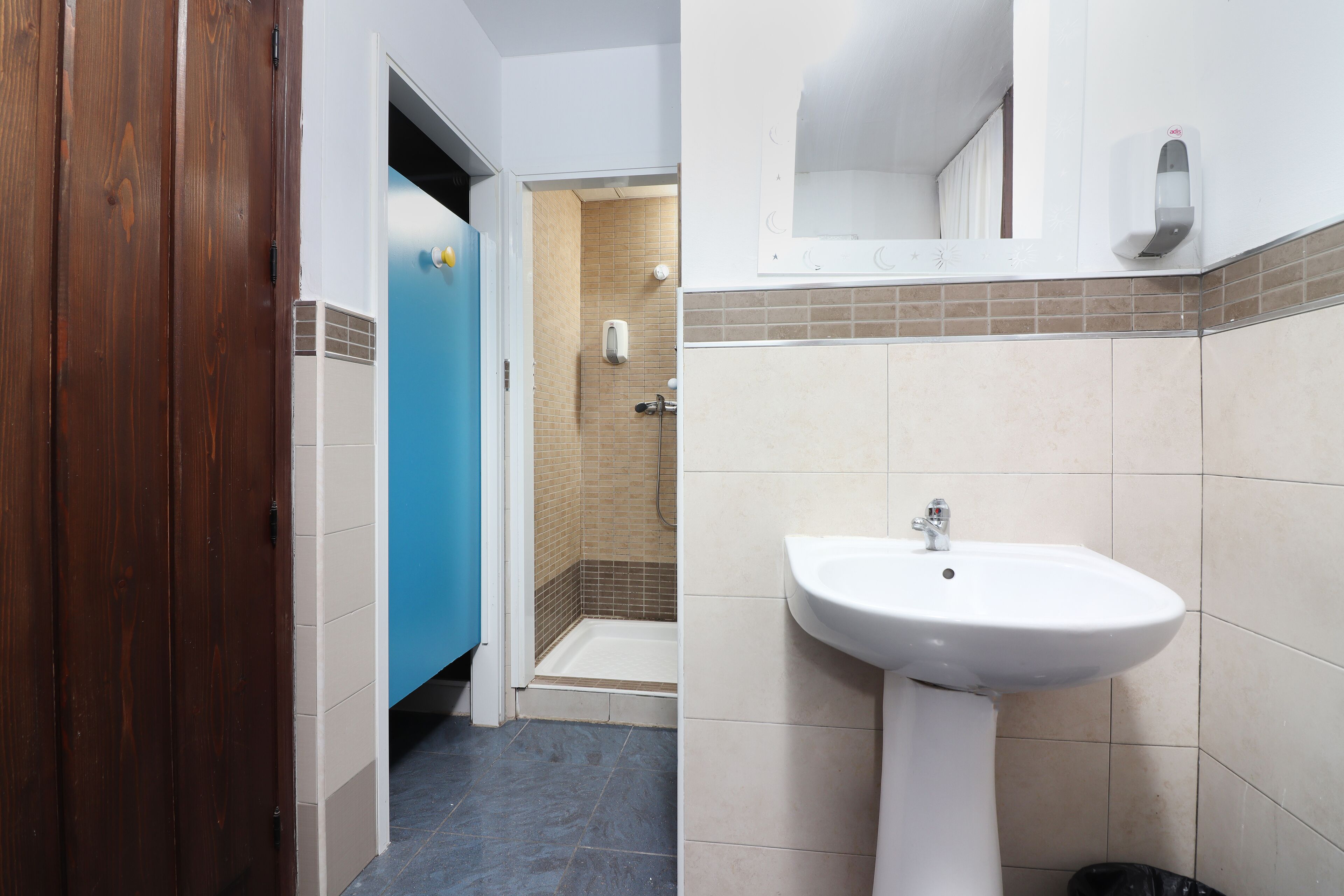 Ein Badezimmer mit einem weißen Waschbecken, einer Dusche und einer blauen Tür.