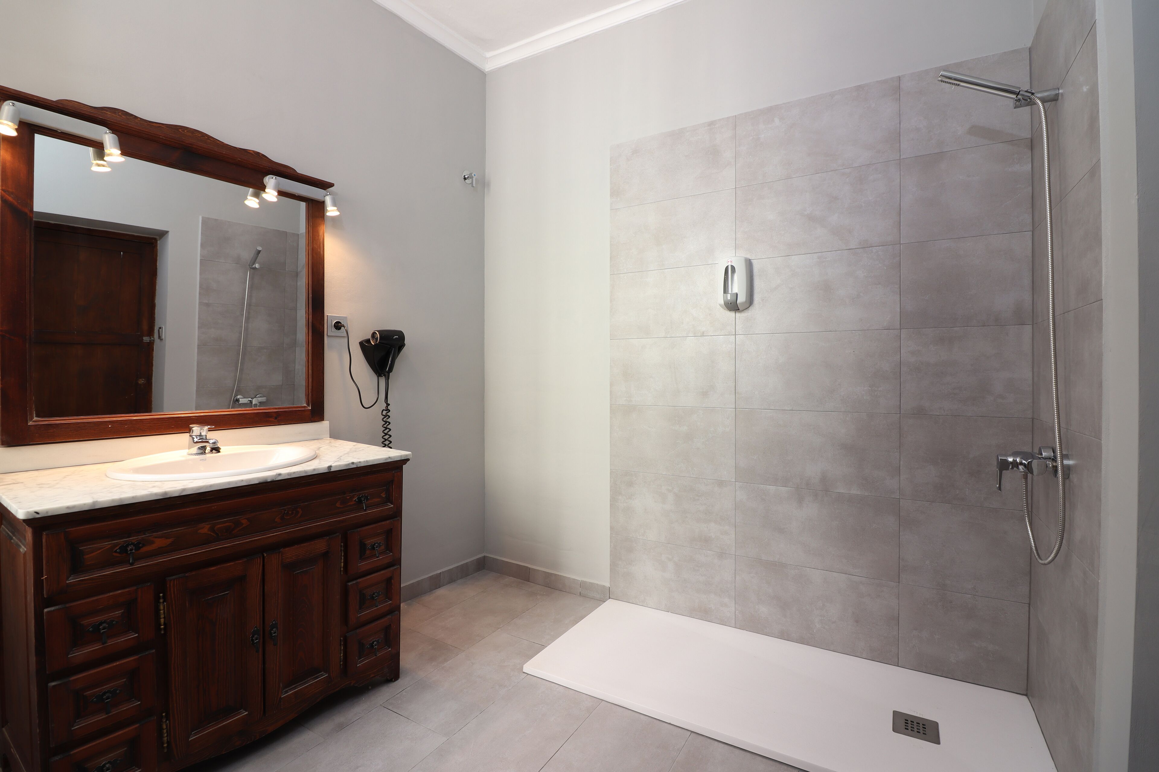 A bathroom with a vanity, sink, mirror, and shower.