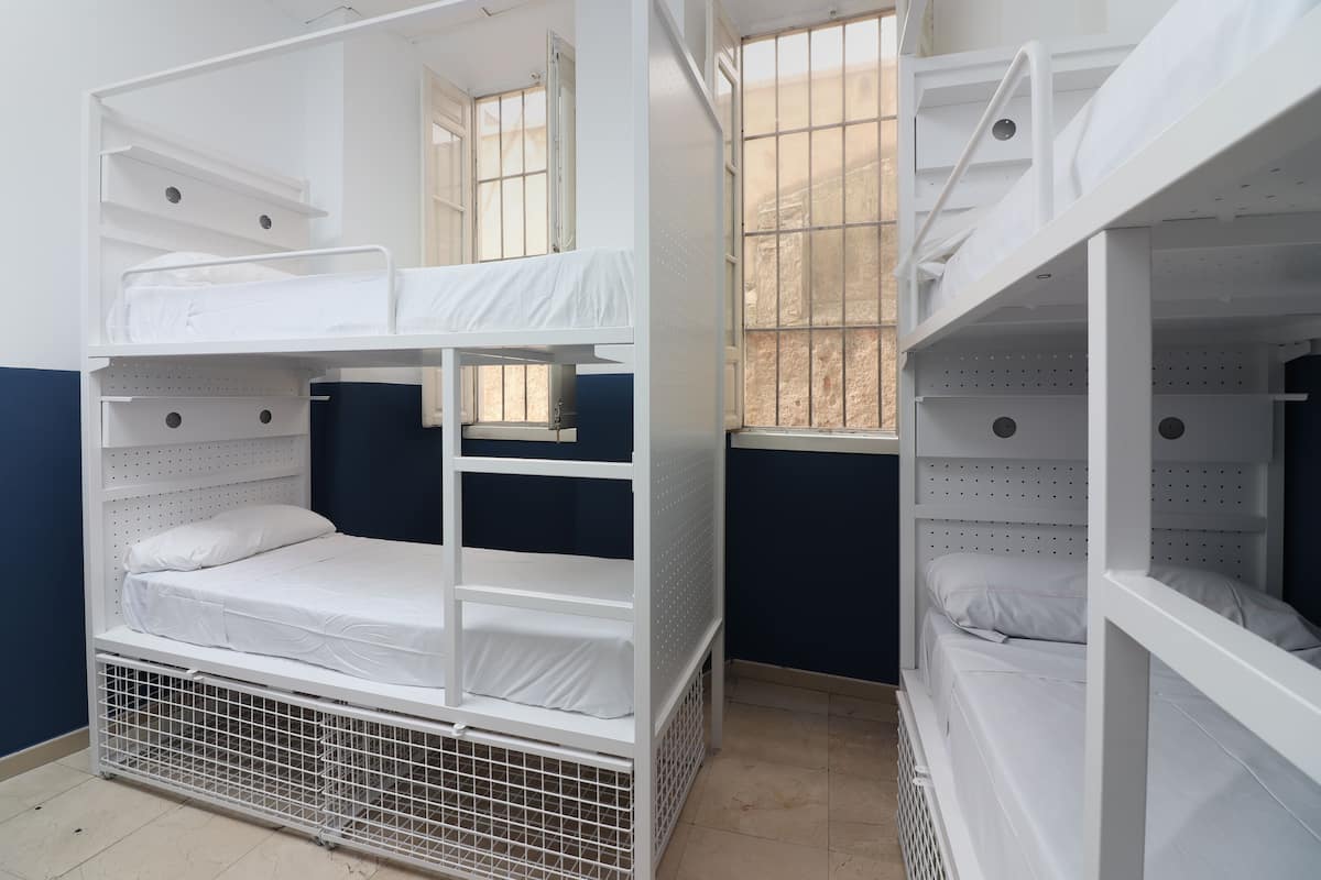 A dormitory room with bunk beds, a window, and a door.