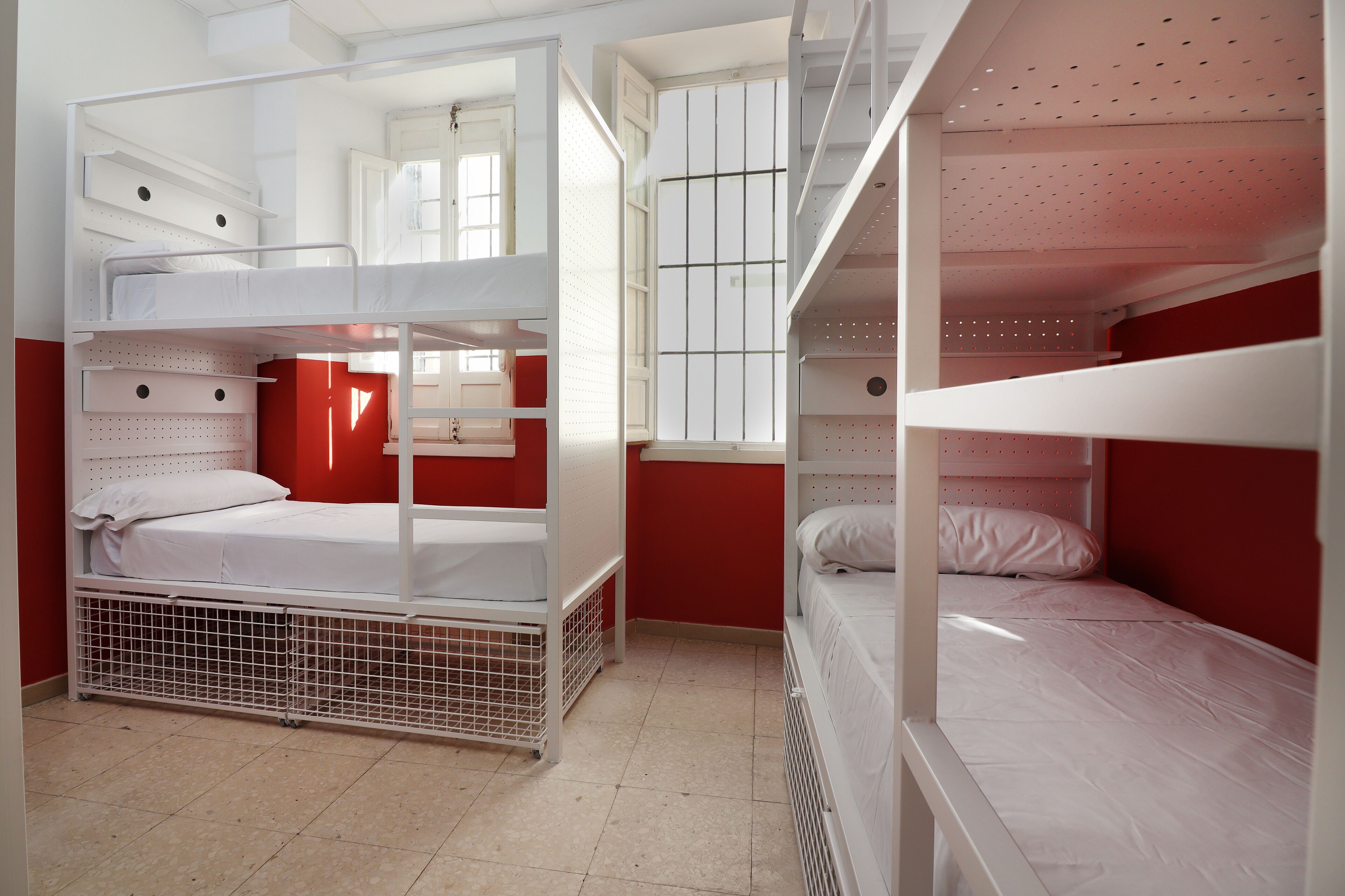 A bunk bed room with a window, a radiator, and a door.