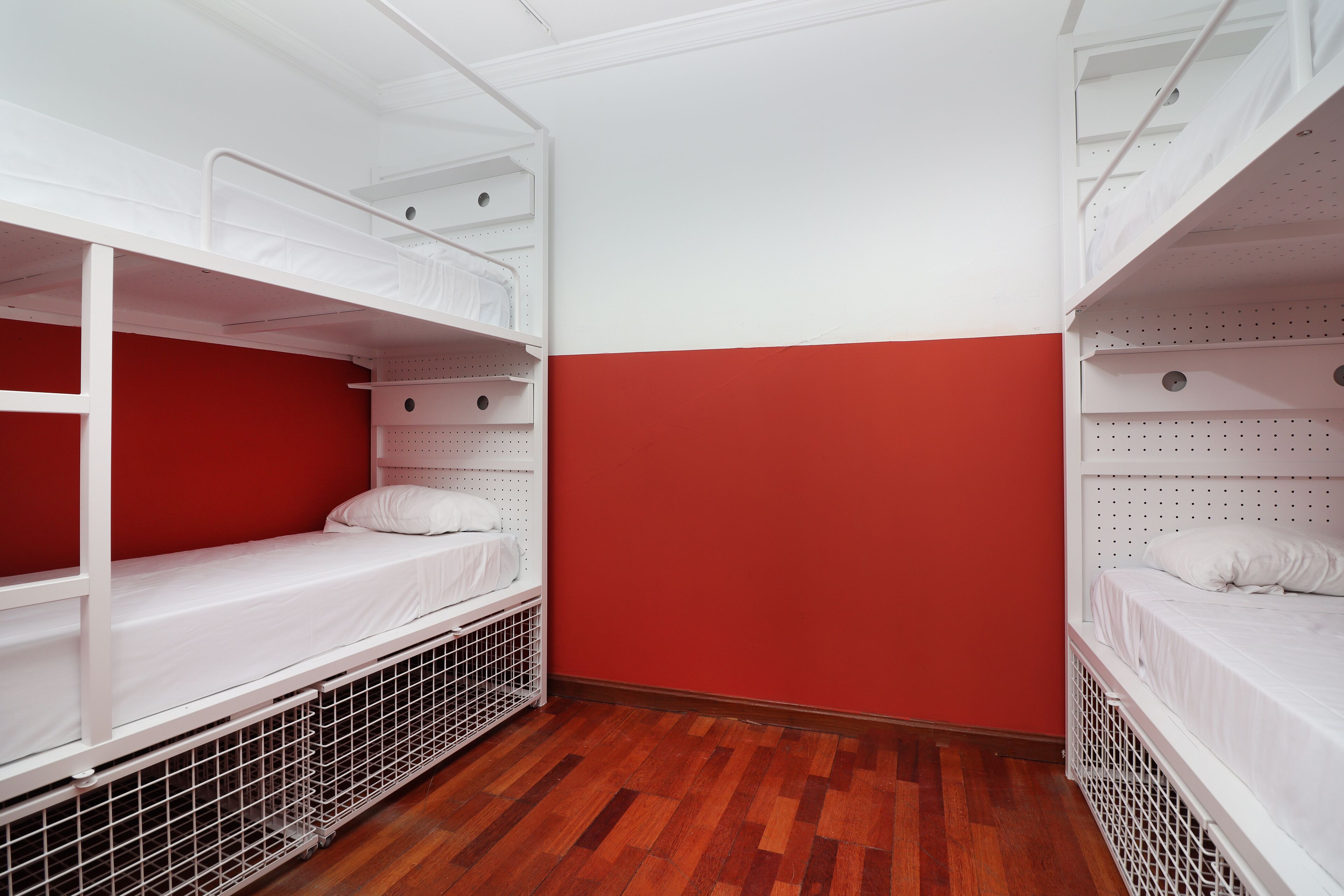 Un dormitorio con camas literas, una pared roja y suelo de madera.