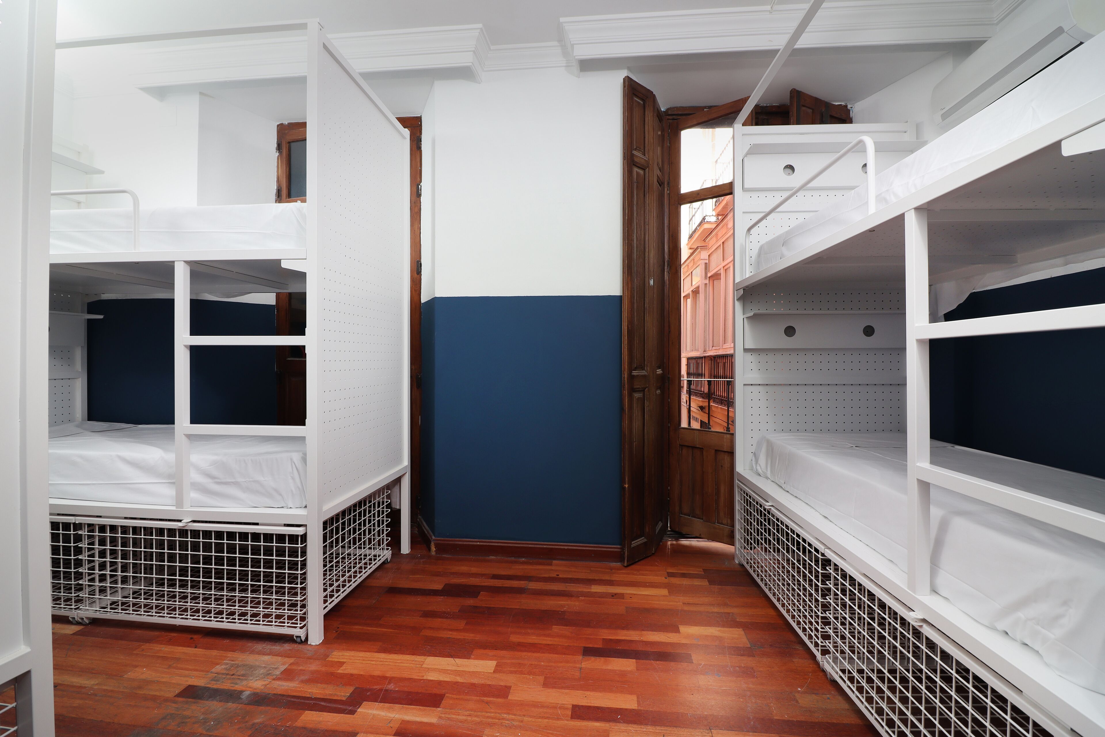 Una habitación con literas, piso de madera y una pared azul decorativa.