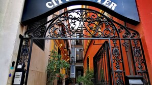 Entrada a Feel Hostels City Center, con ornamentales puertas de hierro y un camino despejado hacia el interior.