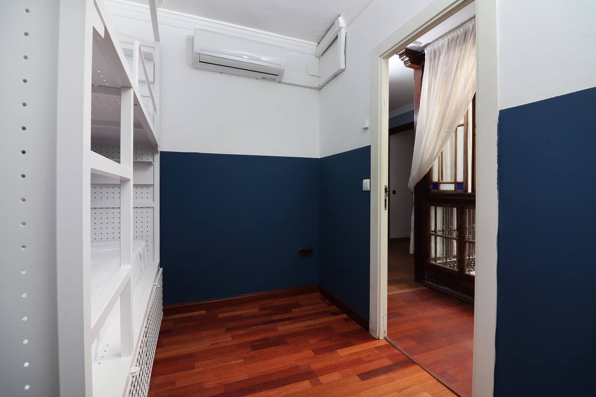A narrow hallway with wooden flooring, white shelving units, and a blue wall.