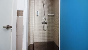 Un baño con ducha, paredes de azulejos y una puerta.