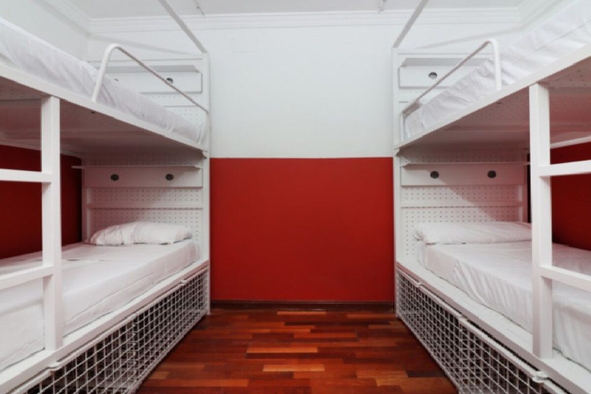 A room with bunk beds, a red wall, and a wooden floor.