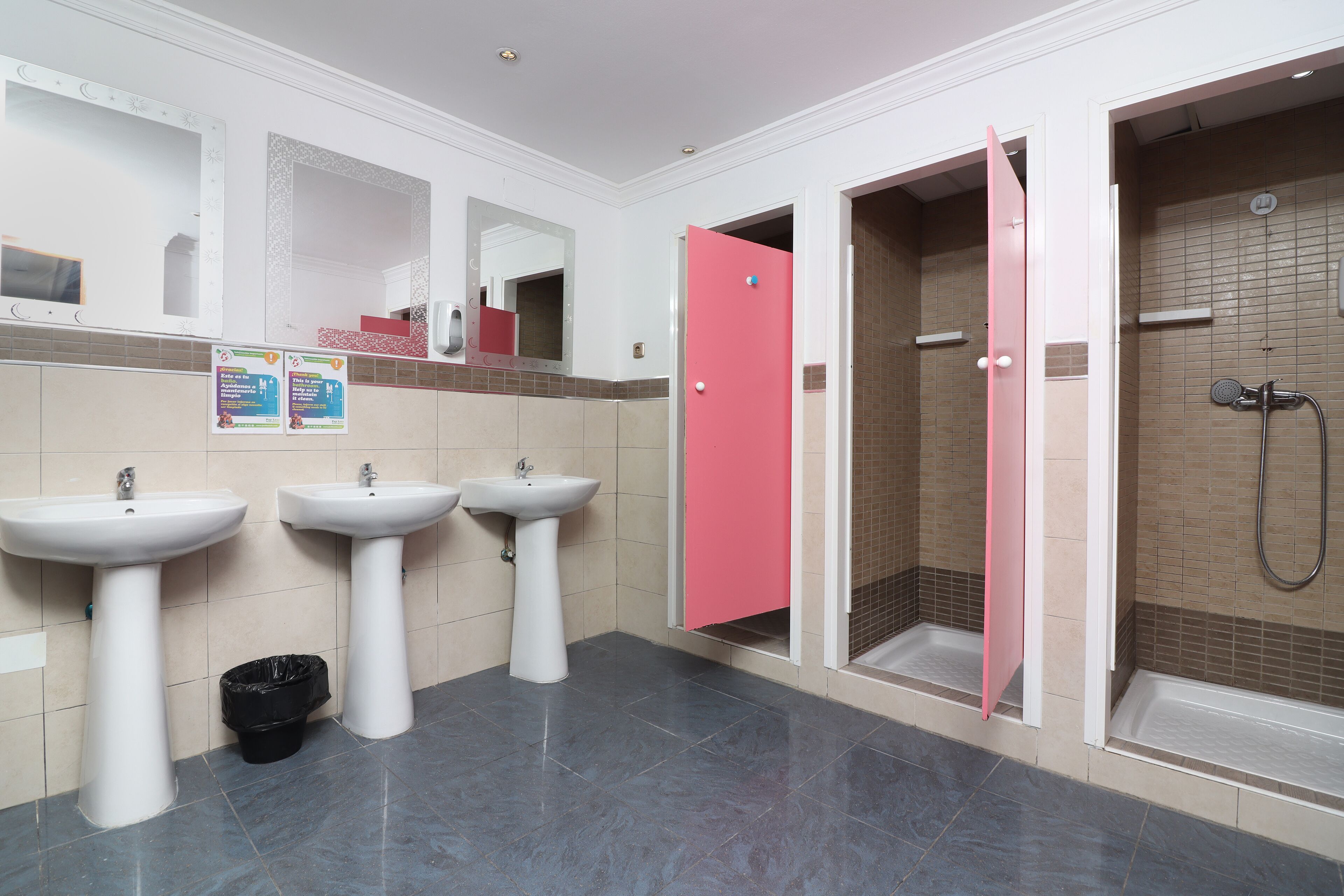 Een badkamer met twee wasbakken, een douche en een roze deur.