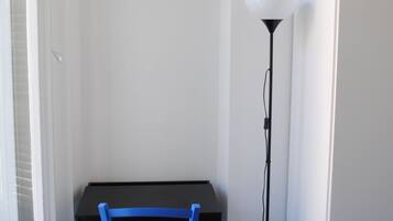 Une pièce avec une table noire, une chaise bleue et un lampadaire.