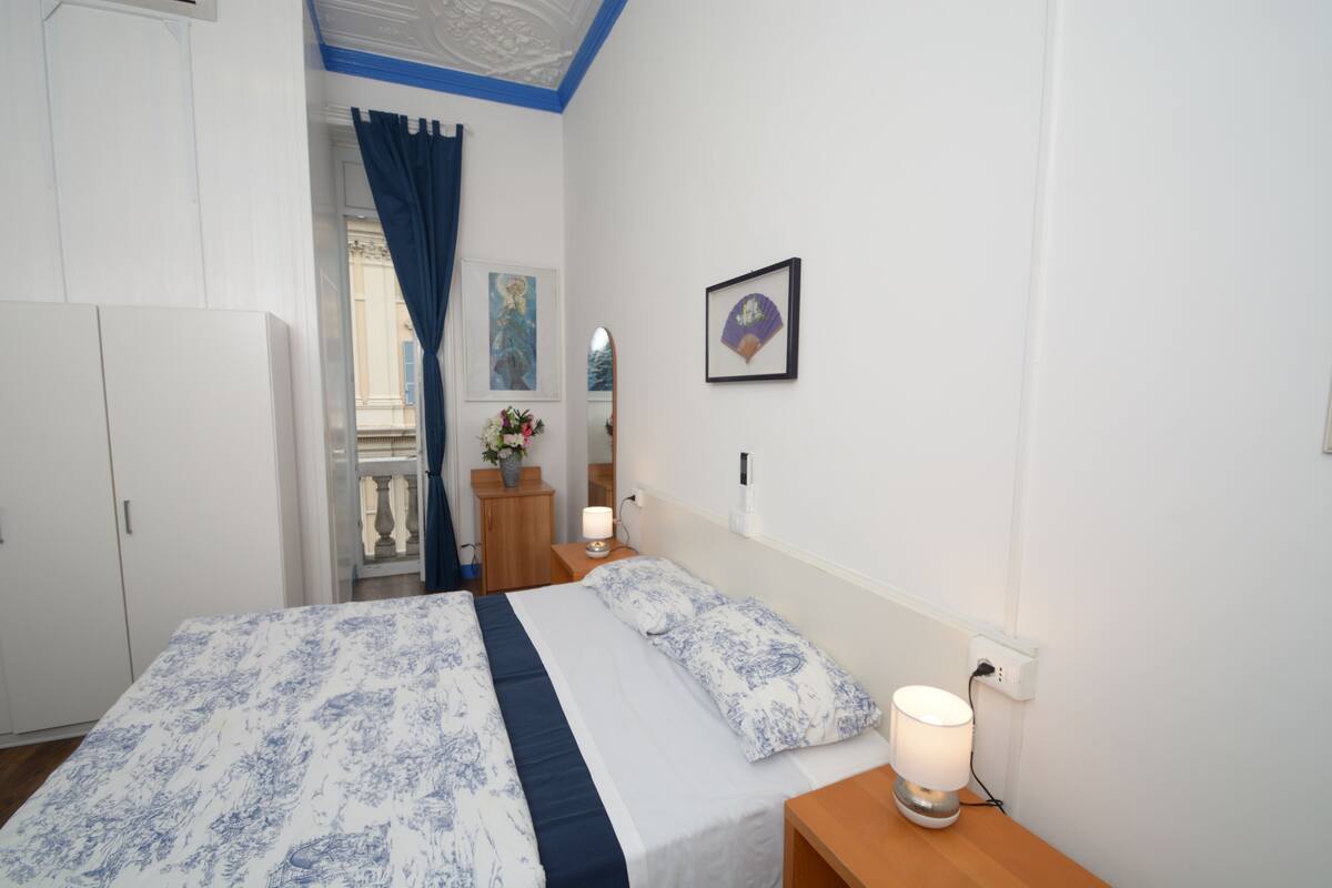 A bedroom with a bed, nightstands, a dresser, a mirror, and a framed picture on the wall.