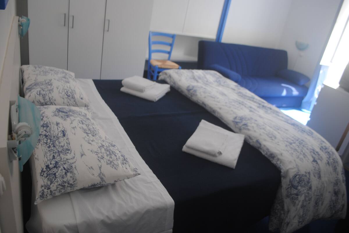 A hotel room with a bed, a chair, and a wardrobe.