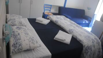 Una camera d'albergo con un letto, una sedia e un armadio.