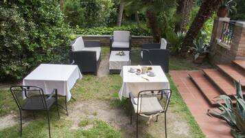 An outdoor patio with a table set for two, surrounded by chairs.