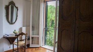 Una habitación con piso de madera, un escritorio con silla, un espejo y un amplio armario de madera.