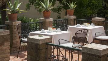 An outdoor patio with stone pillars, metal chairs, and tables set up for dining.
