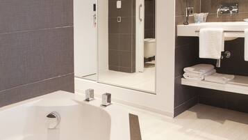 Un baño moderno con una bañera grande, zona de ducha separada y tocador con espejo.