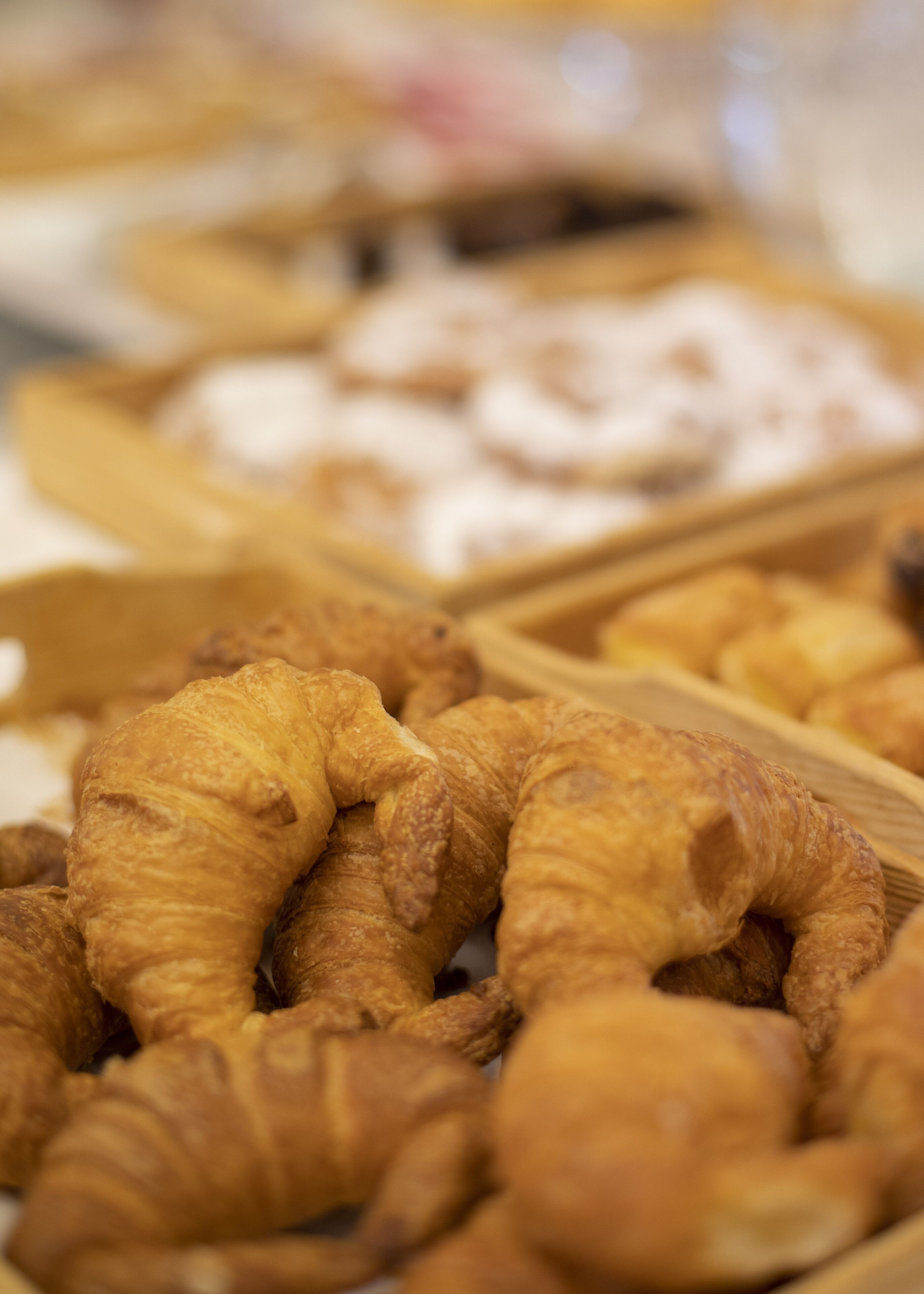 A variety of baked goods, including croissants and other pastries, displayed in wooden trays.