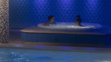 A hot tub with two people in a dimly lit room with blue lighting.