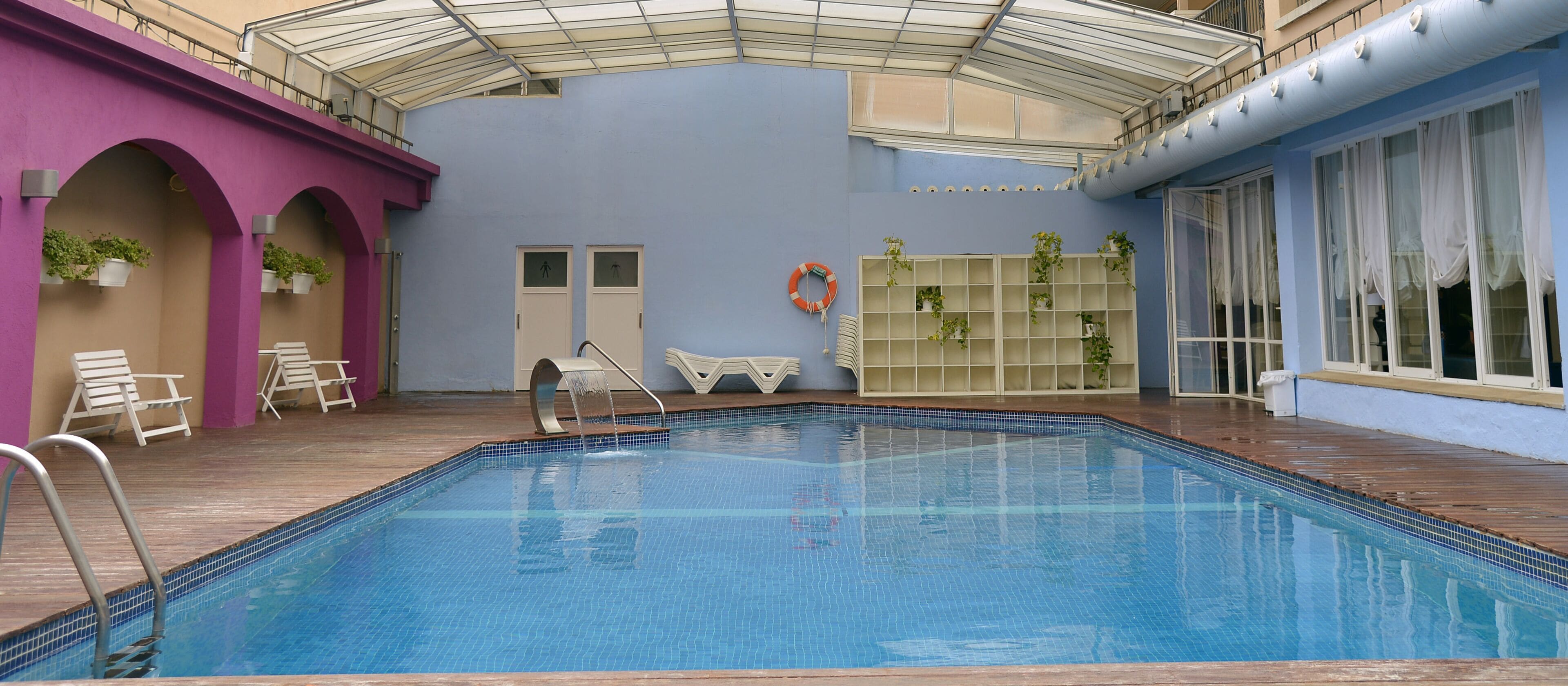 Een binnenzwembad, een buitenzwembad en ligstoelen