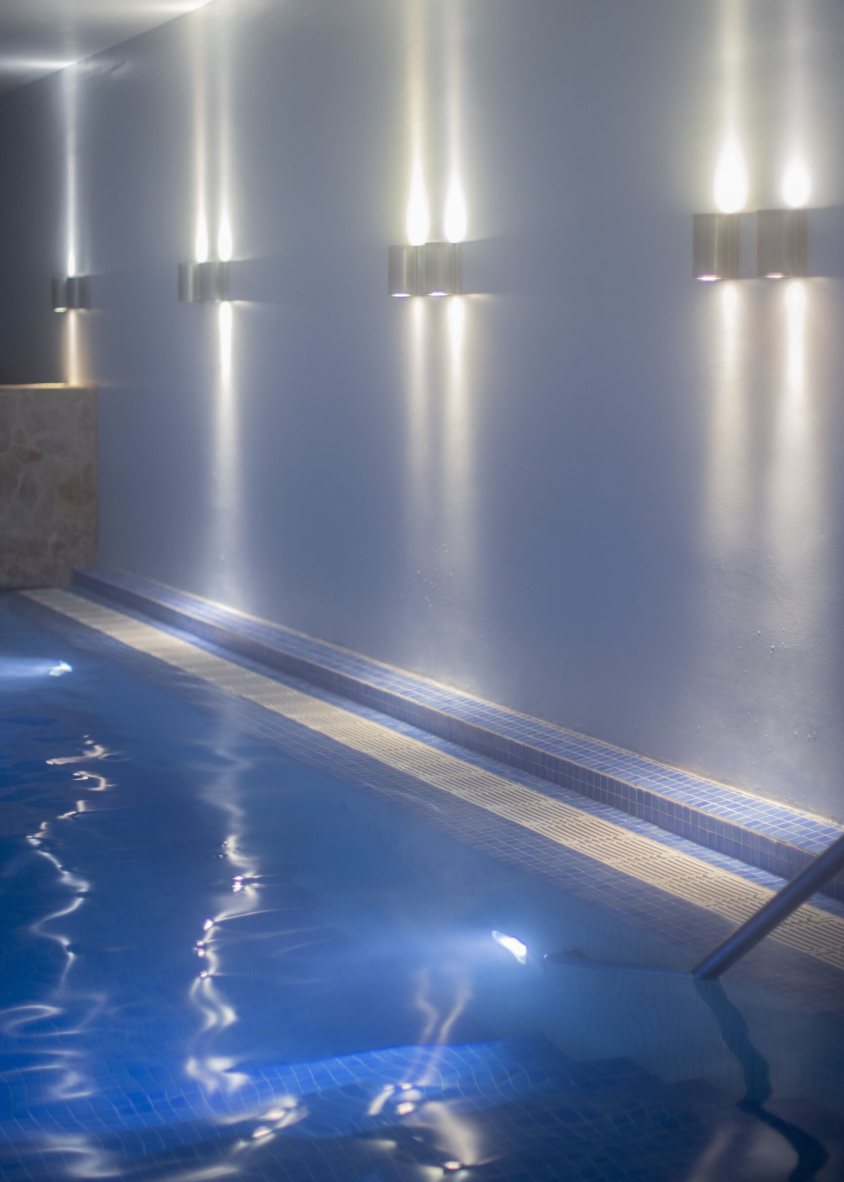Una piscina con escalones azulejados e iluminación empotrada.