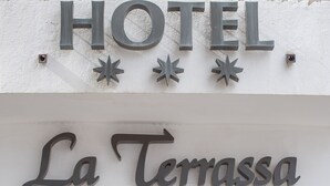 La entrada al Hotel La Terrassa, Restaurante & Spa-Center, con un letrero destacado y una entrada acogedora con plantas en macetas.