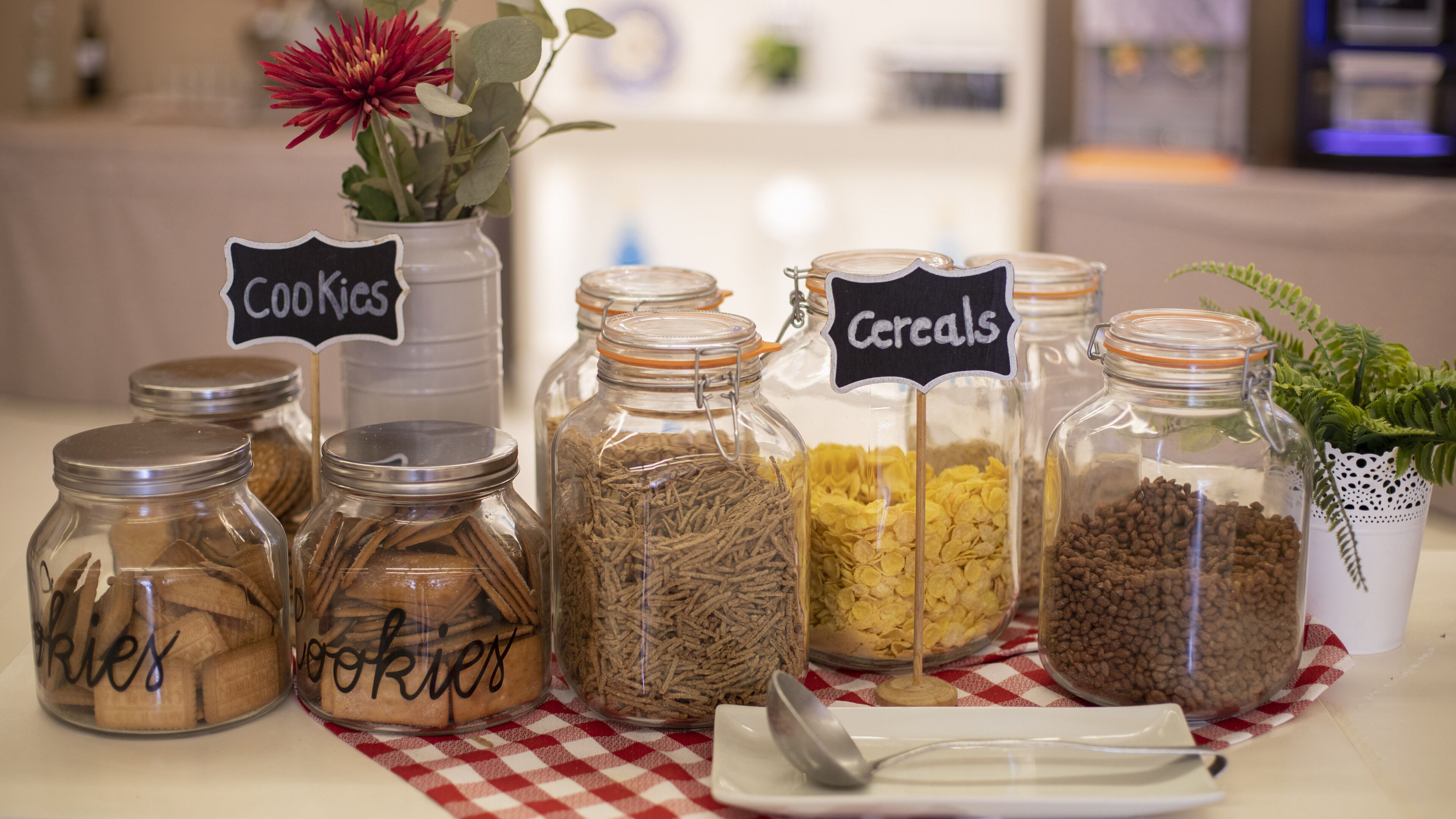 A table with jars labeled "Cookies," "Cookies," "Cereals," and "Cookies," containing various food items.