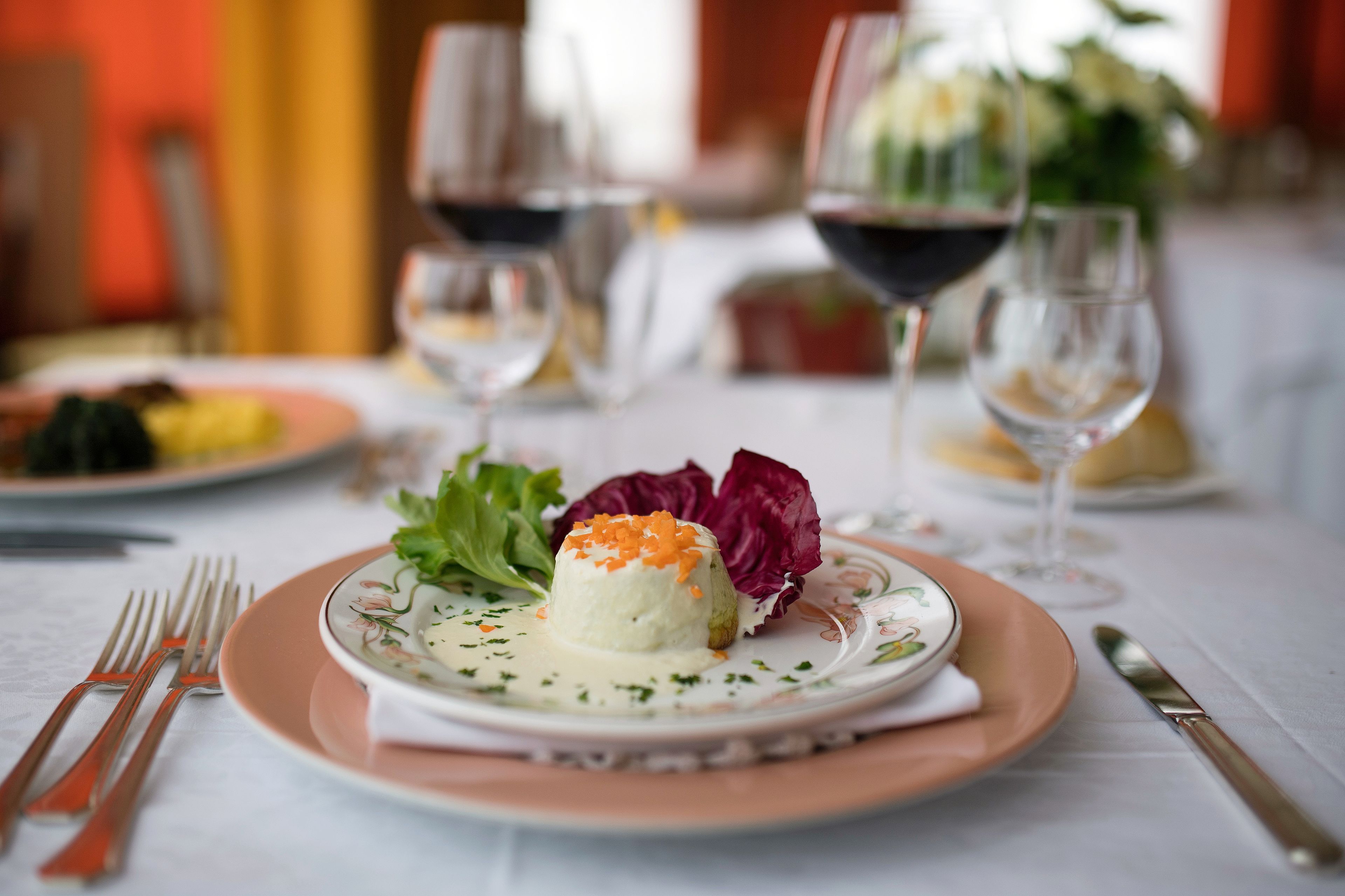 A dining table with a plate of food, wine glasses, and cutlery.