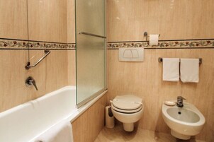 Un baño con bañera, inodoro, bidé y zona de ducha.
