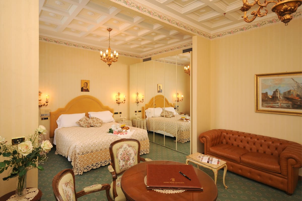 Une chambre d’hôtel avec un grand lit, un canapé, une table ronde et un miroir.