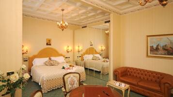 A hotel room with a large bed, a sofa, a round table, and a mirror.
