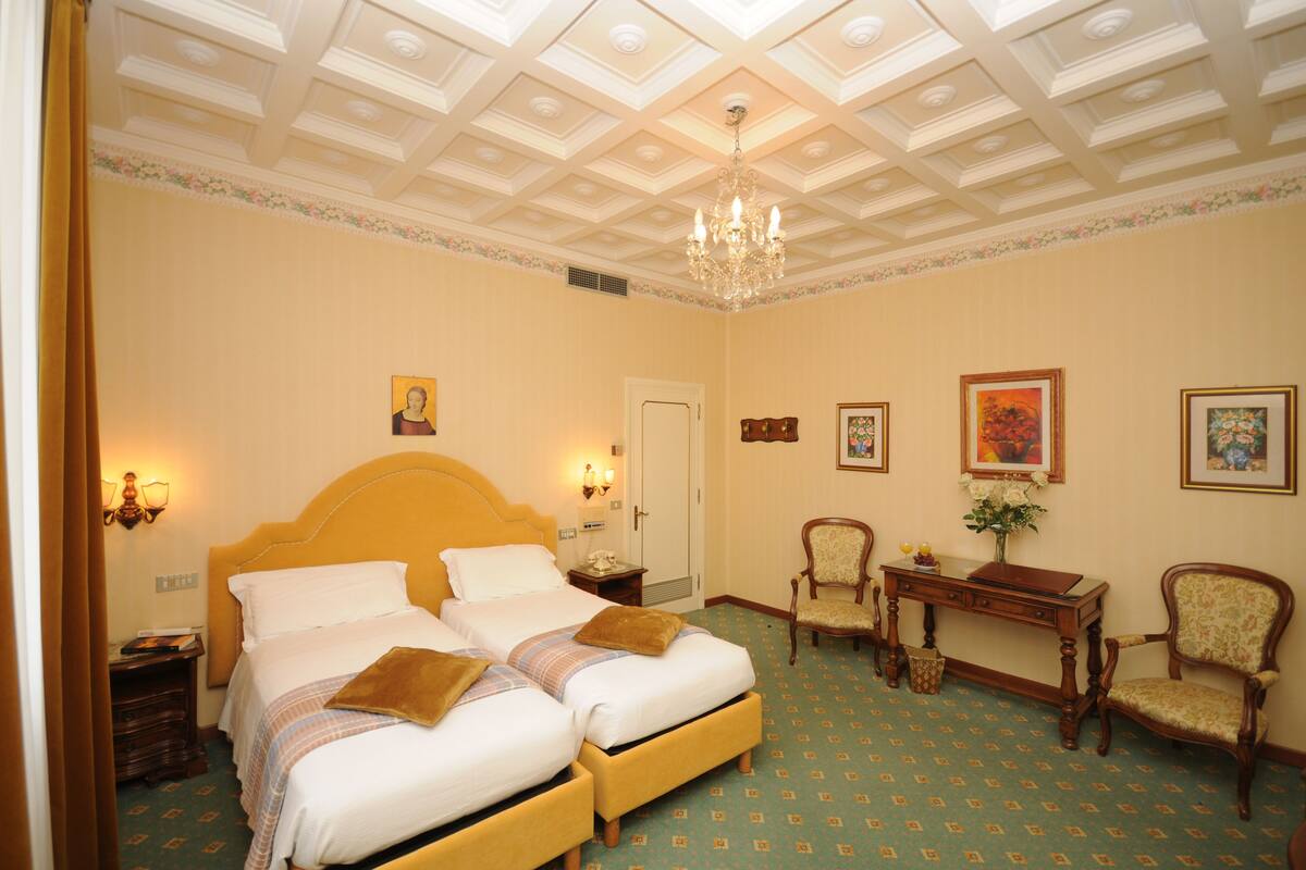 Une chambre d’hôtel avec un grand lit, deux tables de chevet, un bureau et une chaise.