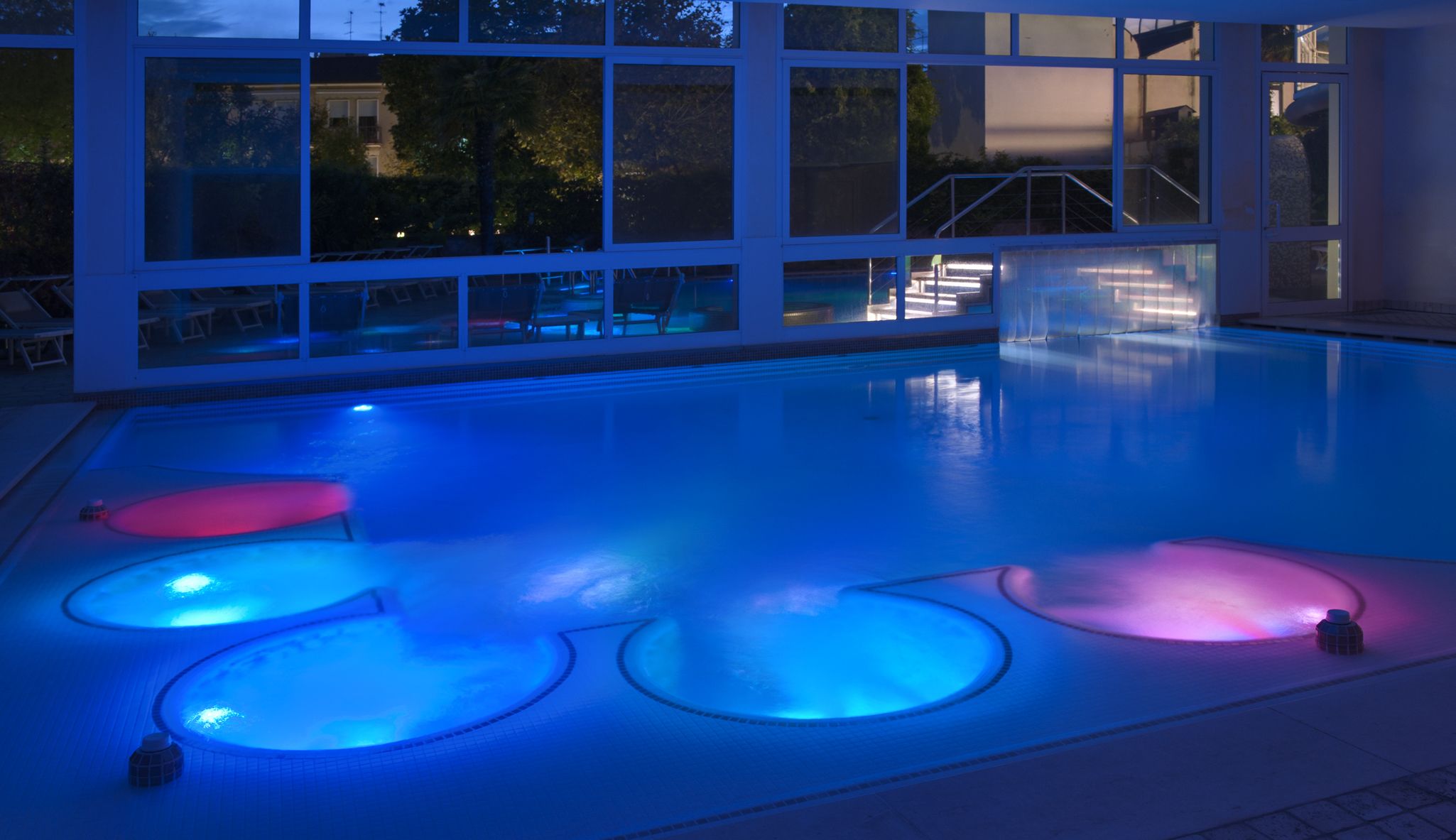 A swimming pool with a view of a building with large windows and a staircase.