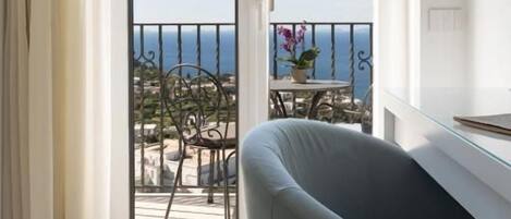 A room with a sliding glass door leading to a balcony with a view of the sea.